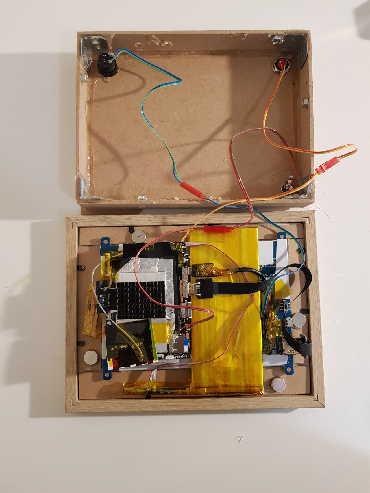 An inside view of the completed unit showing the positions of the battery, motherboard, buttons, cabling and magnets