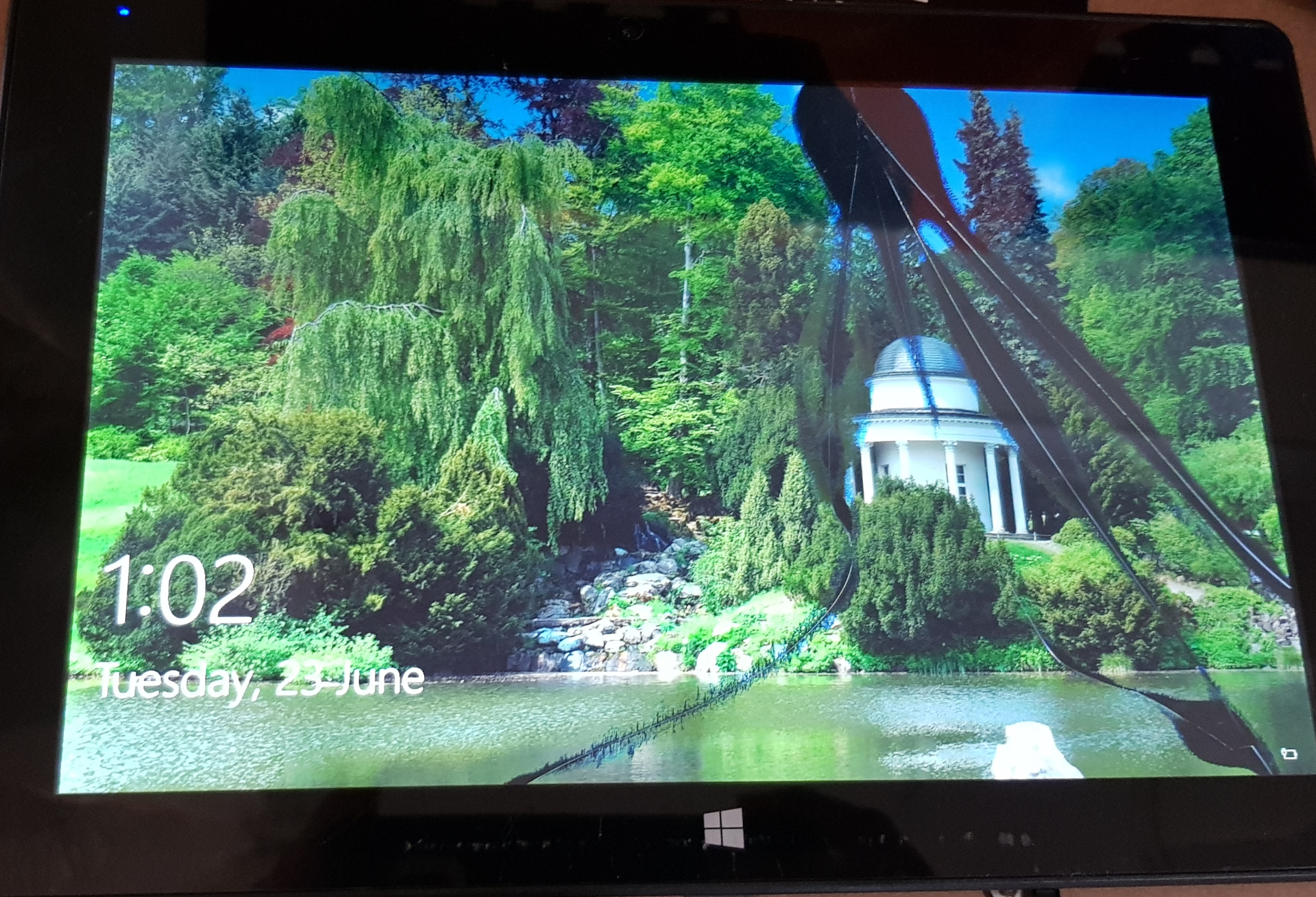 A windows tablet computer with a damaged screen. Cracks are visible and parts of the screen do not turn on.